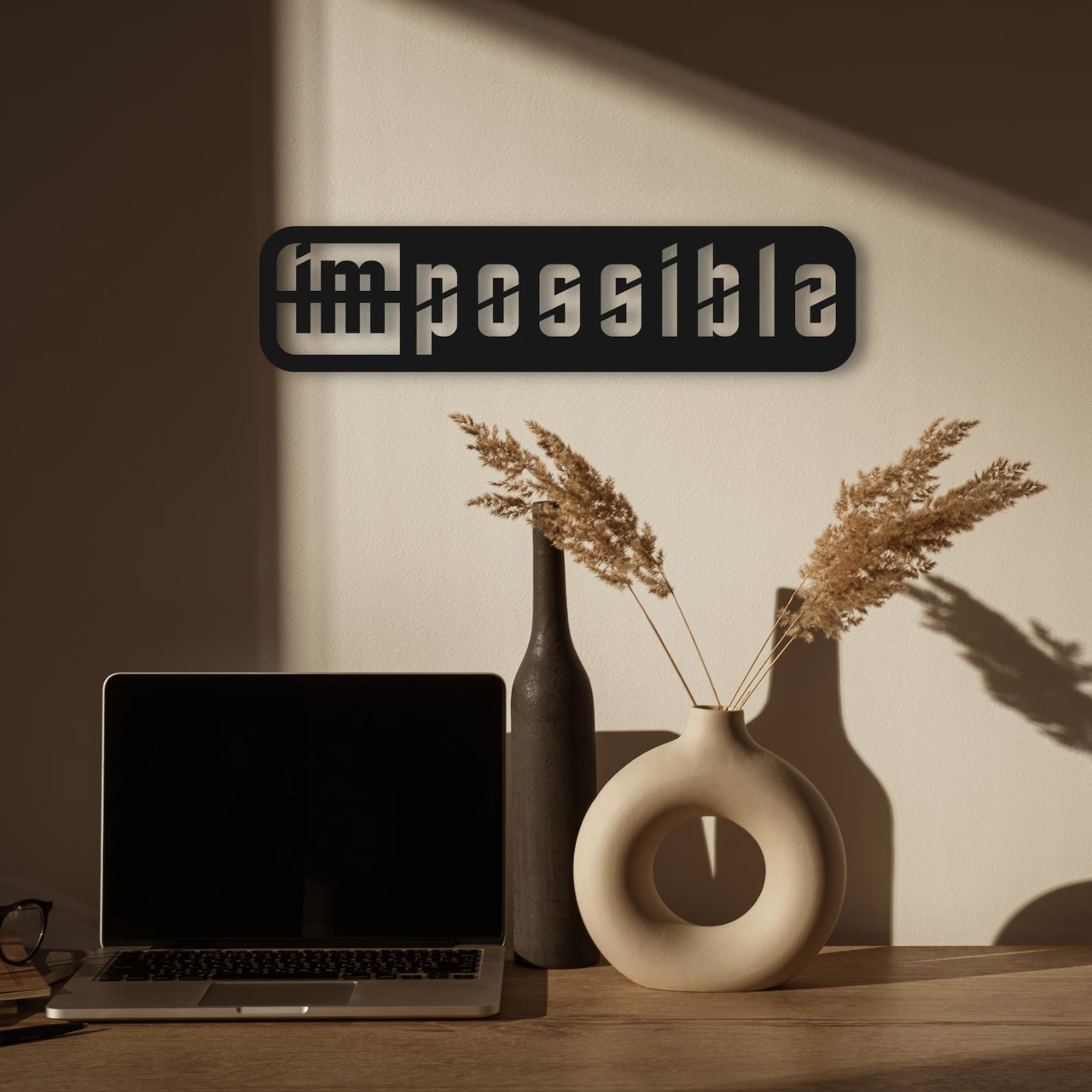 Corporate wall art: Impossible laser-cut metal sign mounted above a desk with a laptop in a warm home office
