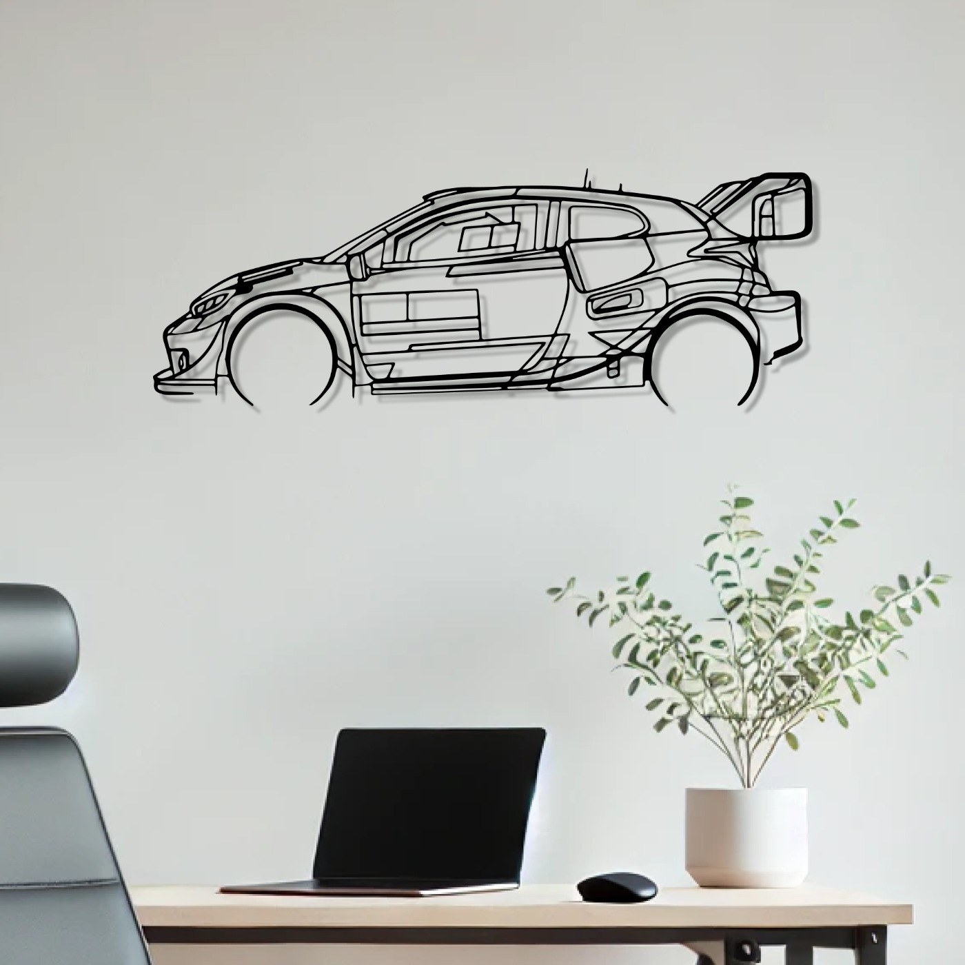 Motorsport wall art: Yaris GR WRC 2022 laser-cut metal rally car silhouette mounted above a white desk with a laptop and plant
