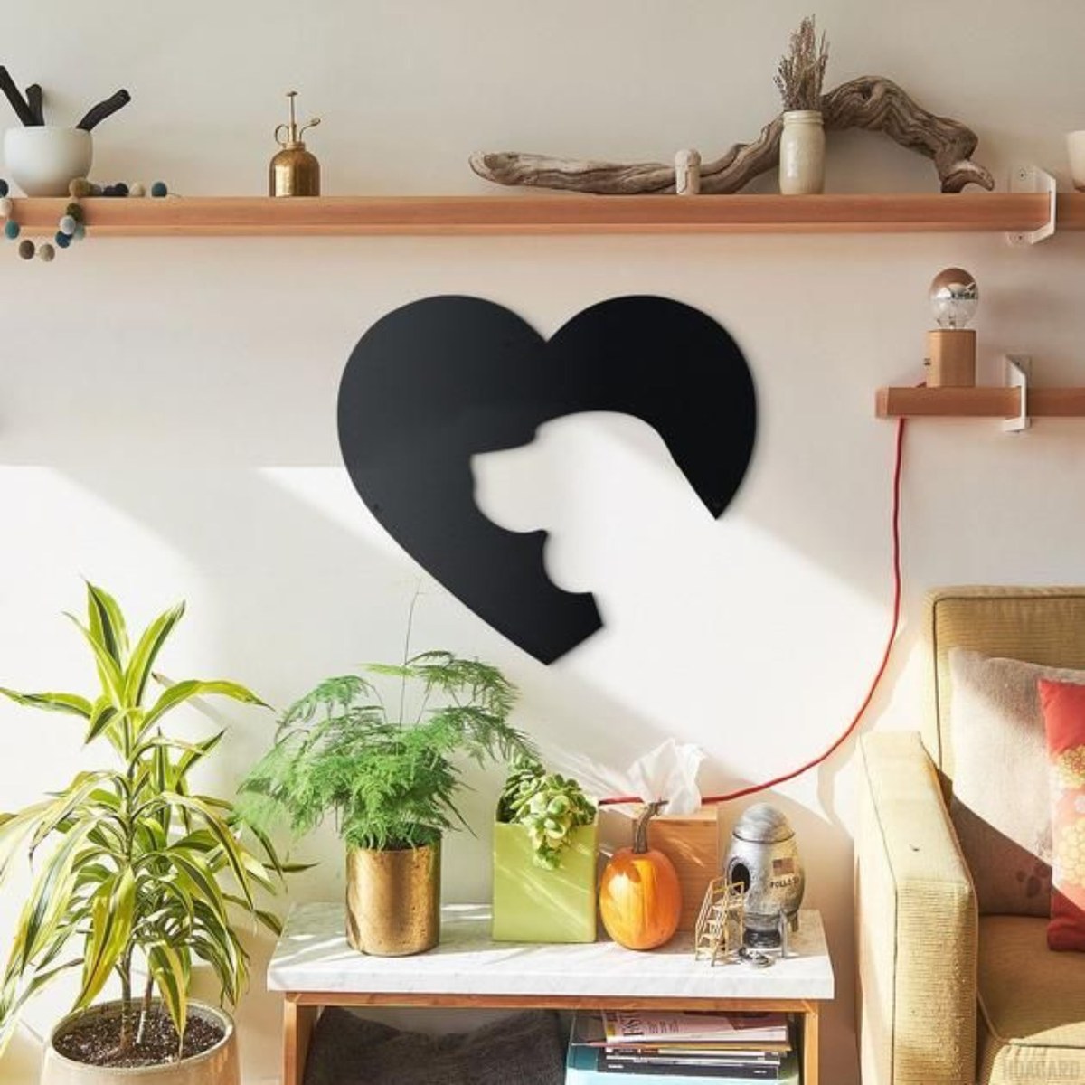 Dog wall art: black laser-cut metal dog heart design on a living room wall above plants