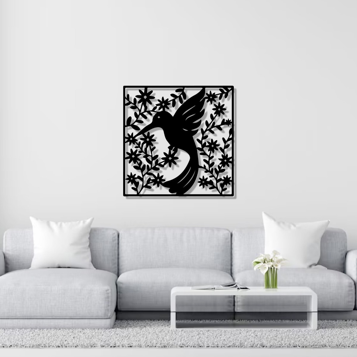Hummingbird wall art: square black laser-cut metal Black-chinned Hummingbird design with flowers and vines, hung above a grey sofa
